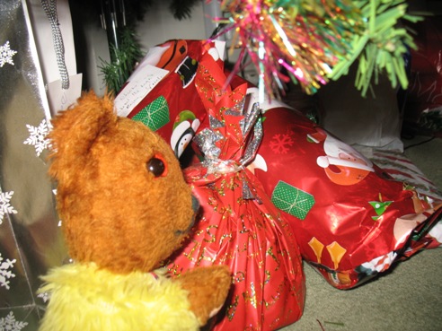 Yellow Teddy checking presents under Christmas tree