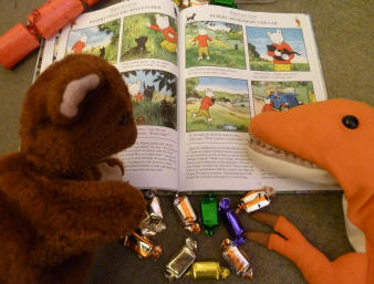 Brown Teddy and Dino reading Rupert Bear book